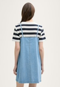 Denim jurk met verstelbare bandjes, uitlopende vorm, lichtblauwe kleur en een contrasterend zwart-wit gestreept t-shirt eronder.