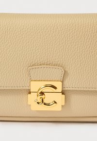 Μπεζ δερμάτινη τσάντα χειρός με υφή. Διαθέτει χρυσό κούμπωμα με το στυλιζαρισμένο λογότυπο «C». Συμπαγής ορθογώνιο σχήμα.