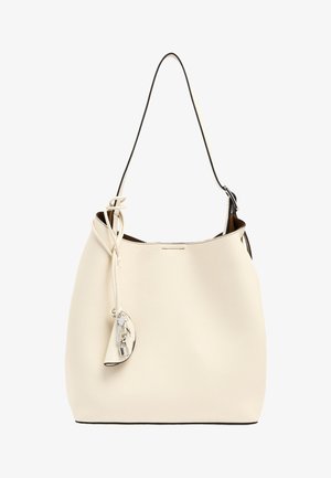 Beżowa skórzana torebka na ramię z jednym czarnym paskiem oraz małą przymocowaną saszetką z srebrnym zamkiem błyskawicznym i zawieszką w kształcie kłódki.