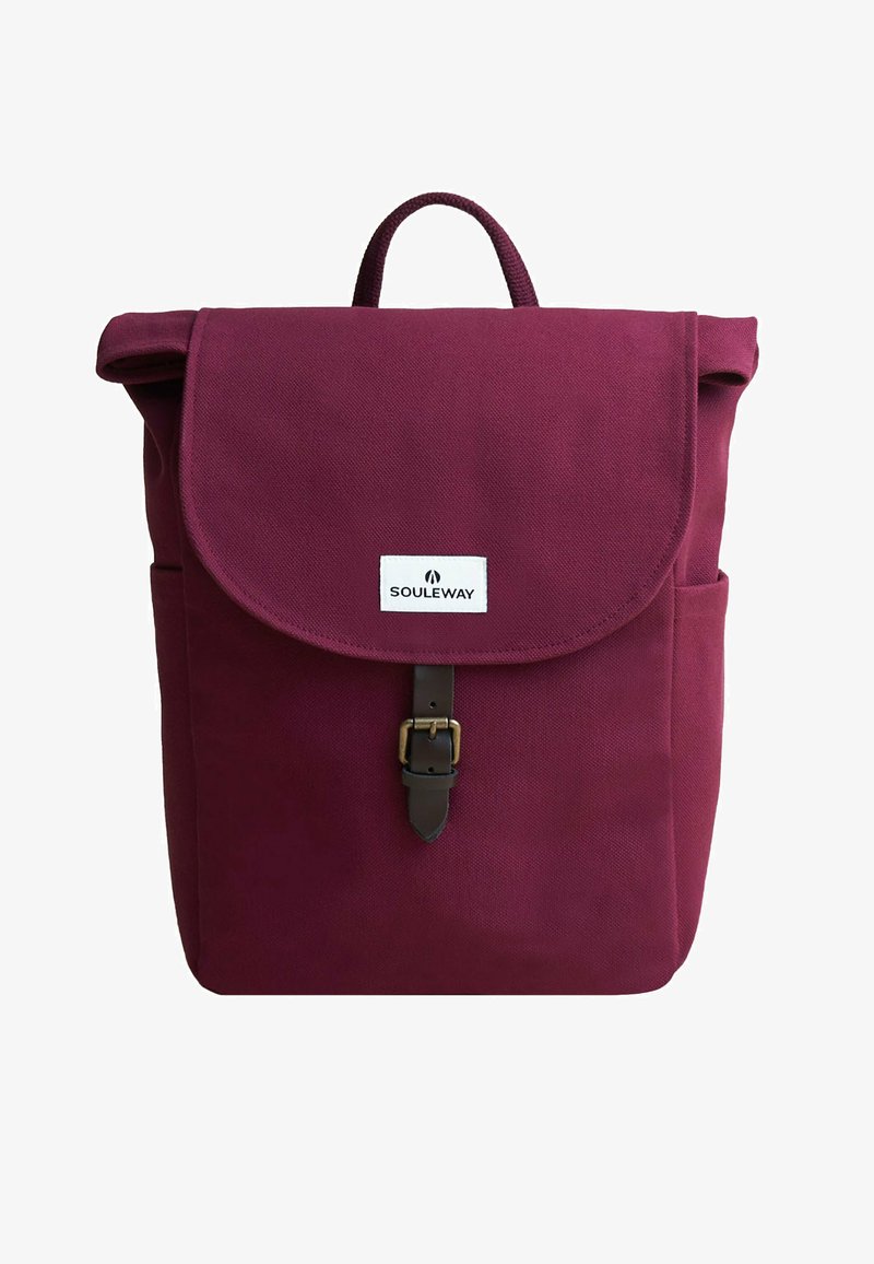 Vinröd kanvas ryggsäck med en vikbar flap, läderknäppning och sidofickor. Har ett handtag på toppen och en logotyp patch på framsidan.