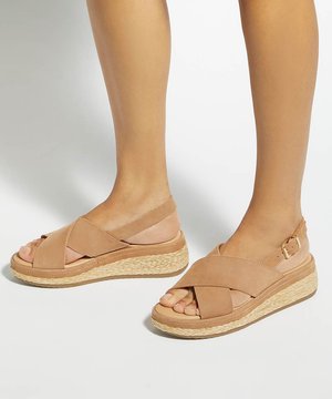 Sandales compensées couleur camel avec des brides croisées et des boucles à la cheville, portées pieds nus, présentées sur un fond clair.