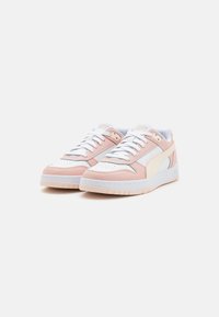 Sneakers rosa e bianchi con tomaia in pelle liscia, punta perforata, lacci bianchi e suola in gomma. Presentano un logo laterale in crema.