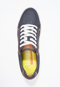 Námořnické denimové tenisky s bílými tkaničkami, hnědými koženými detaily a žlutou stélkou se značkou a velikostí. Rovná gumová podrážka.