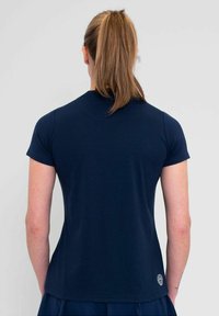Camiseta de manga corta azul marino con un diseño ajustado, textura suave de algodón y un pequeño detalle de logo cerca del dobladillo en la parte trasera.