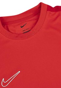 Rotes Nike Sport-T-Shirt mit rundem Kragen, das ein schwarzes Swoosh-Logo und eine Netzstruktur am Kragen aufweist.
