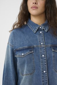 Camicia in denim con colletto button-down, due tasche frontali con chiusura a bottone e una sfumatura di blu sbiadito; texture morbida e vestibilità rilassata.