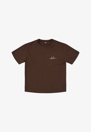 Brun bomullströja med korta ärmar och rundad halsringning, prydd med en vit skrivstilssignatur på vänster bröst.