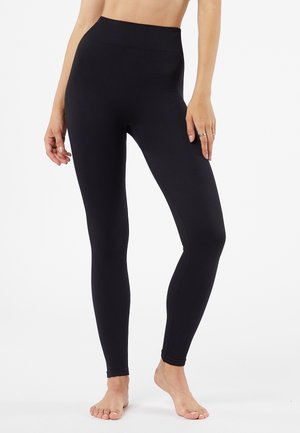 Leggings noirs à côtes avec une taille haute, présentant une texture lisse et un design près du corps. Convient pour une utilisation décontractée ou active.