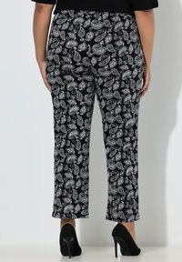 Černobílé kalhoty s paisley vzorem, úzkého střihu a s lemem končícím nad kotníkem, vyrobené z měkké, pružné látky.
