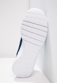 Nike-tennarit, jolla on teksturoitu laivaston sininen päällinen ja valkoinen kumipohja, jossa on kuviointi. Sivunäkymässä näkyy brändäys pohjassa.