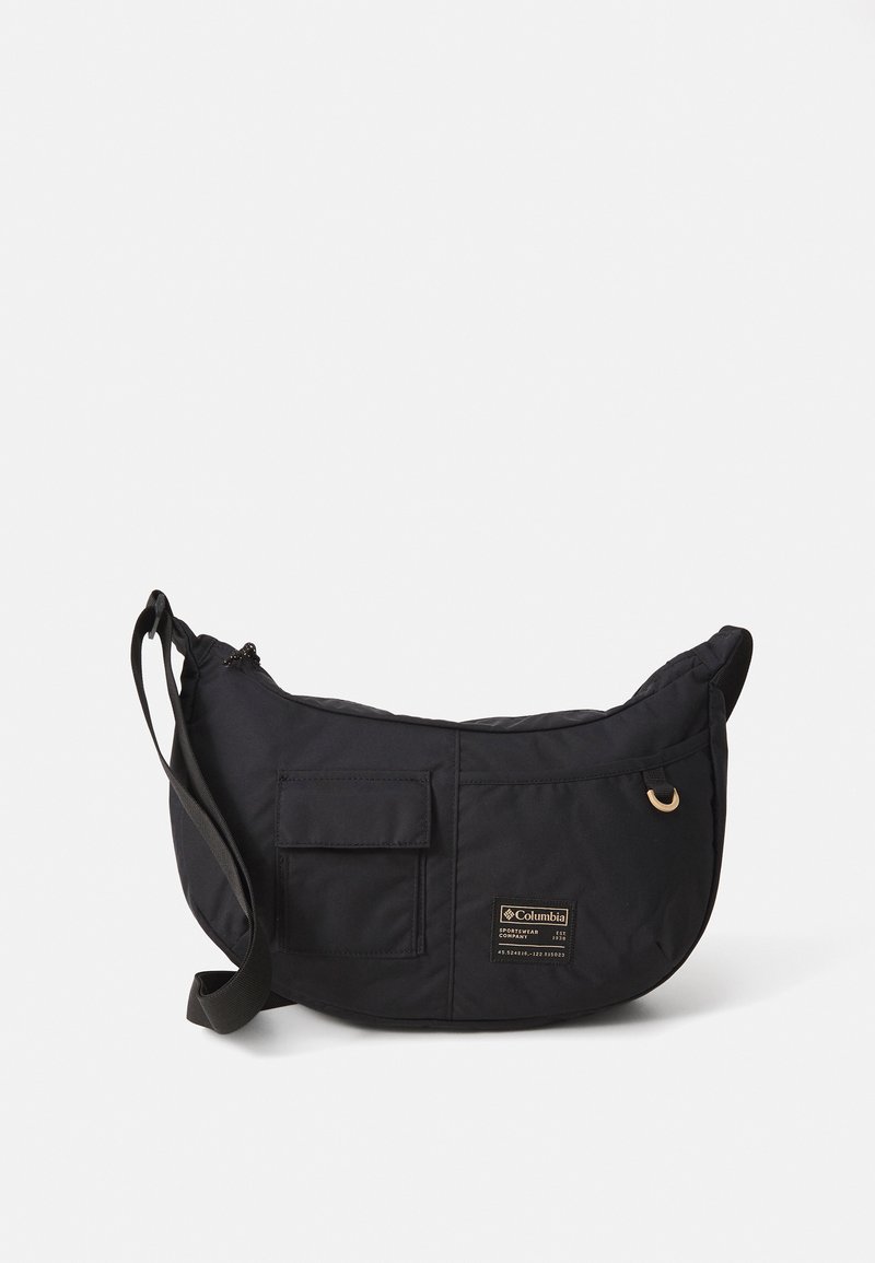 Black crescent-shaped shoulder bag with adjustable strap, front flap pocket, fabric loop, and Columbia brand label on plain background.