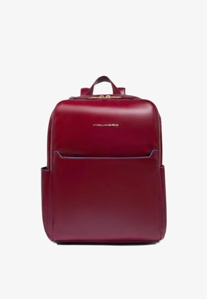 Roter Lederrucksack mit glatter Textur, ausgestattet mit einem oberen Griff, Reißverschluss und Vordertasche. Logo auf der Vorderseite zu sehen.