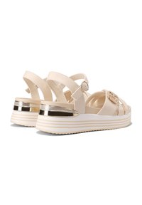 Sandali platform beige con design a fascia incrociata, fibbia regolabile e fascia metallica sulla suola bianca testurizzata.