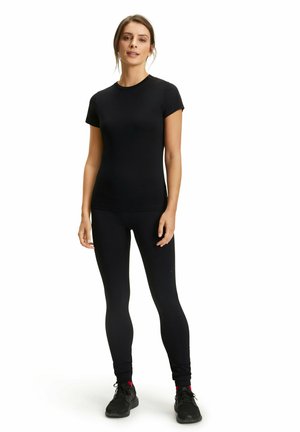 Czarna dopasowana koszulka sportowa i legginsy wykonane z elastycznego materiału. Krótkie rękawy, okrągły dekolt, gładka struktura i minimalna marka.