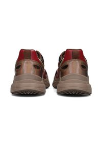 Sneakers marroni e rossi con accenti in rete, dotati di una suola in gomma testurizzata, aperture posteriori e dettagli di cucitura a contrasto.
