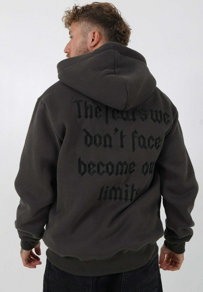 Donkergrijze hoodie van een katoenmix, met grote zwarte tekst op de achterkant. Het heeft een buidelzak en ribgebreide cuffs en zoom.