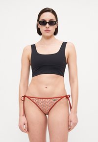 Top de bikini negru cu decolteu pătrat, acompaniat de slipuri de bikini cu un model în nuanțe de portocalie și crem, cu legături pe laterale.