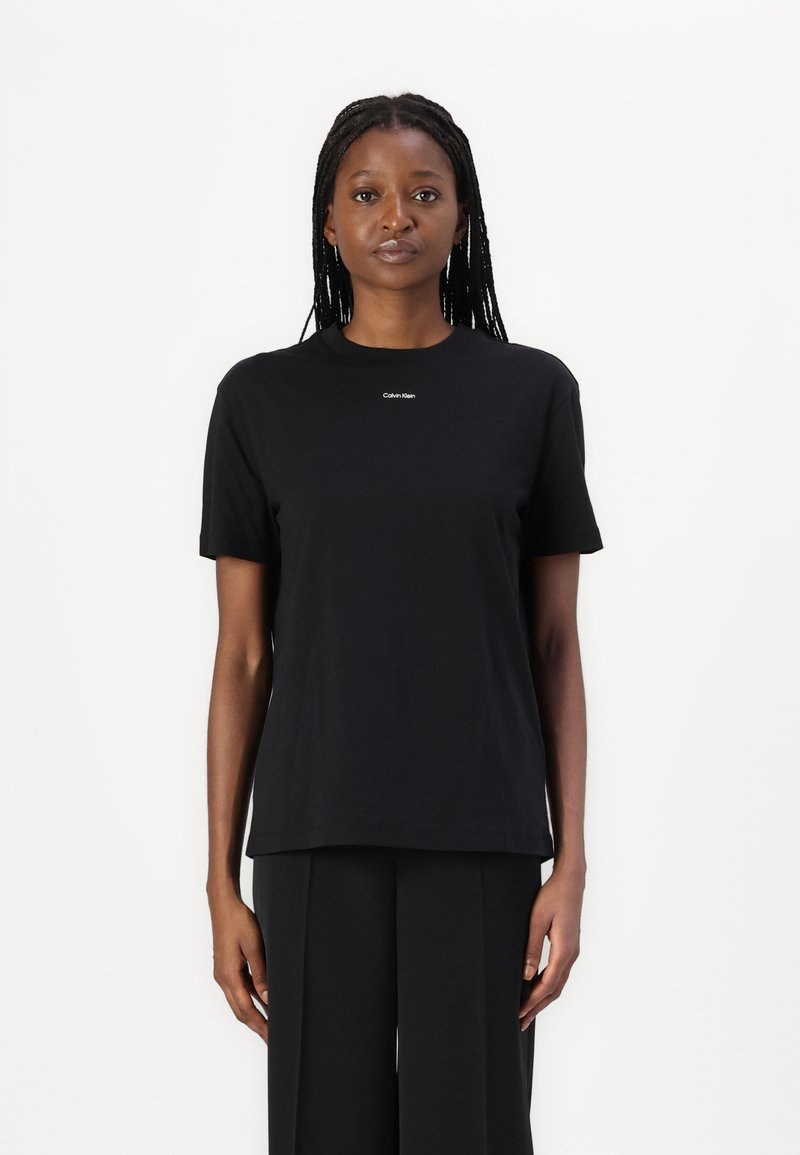 Sort bomulds t-shirt med rund hals, korte ærmer og lille hvid "Calvin Klein" logo på brystet. Glat tekstur, standard pasform.