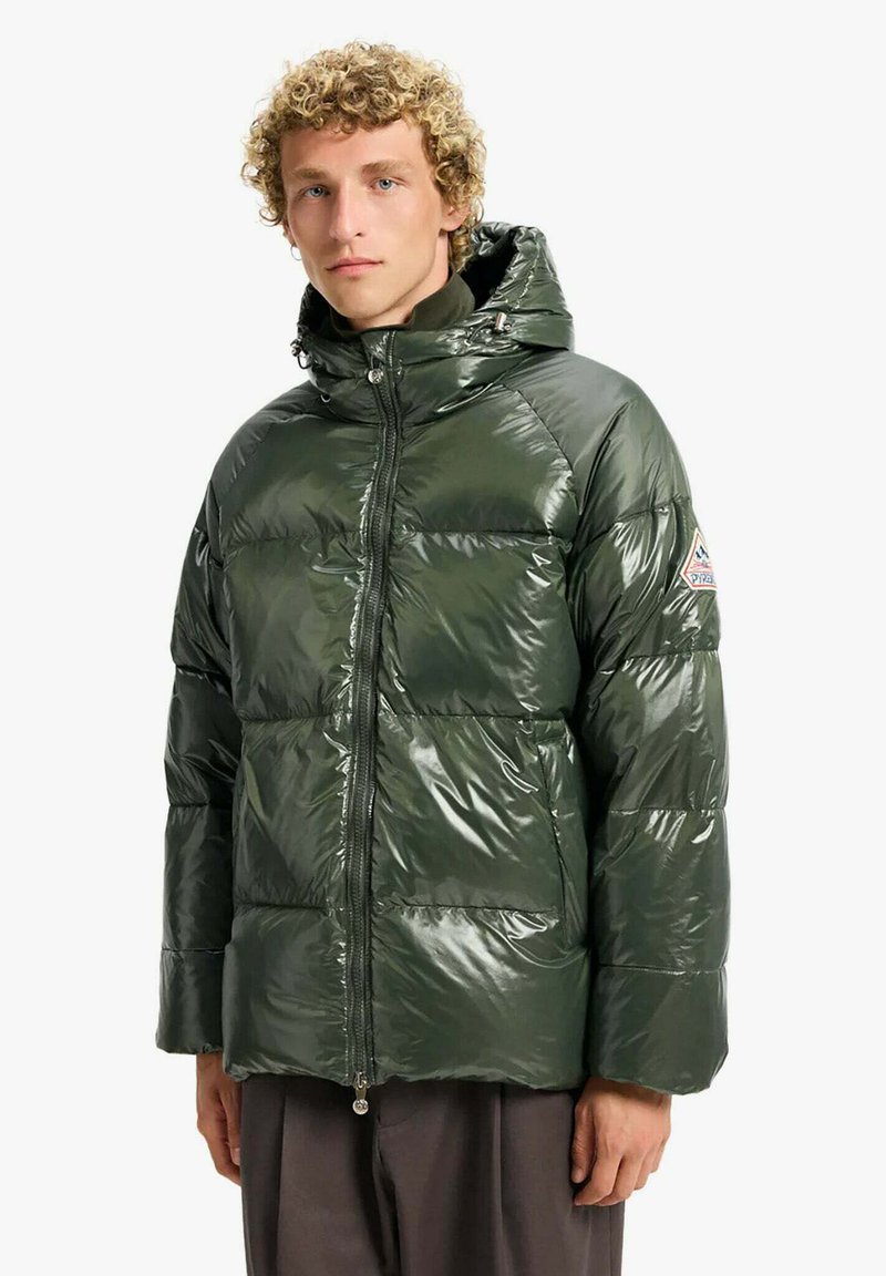 Chaqueta acolchada verde brillante con capucha, cierre frontal con cremallera y bolsillos laterales. Presenta un parche con logotipo triangular en la parte superior del brazo.