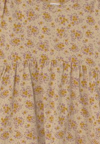 Kwiatowa sukienka z beżowego materiału w małe żółte i fioletowe kwiaty, z zebranym stanikiem i krótkimi rękawami. Teksturowany, lekki materiał bawełniany.