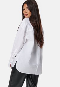 Witte button-up shirt met een ontspannen pasvorm, lange mouwen en zijsplitten. De stof lijkt soepel en licht van gewicht te zijn.