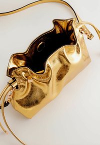 Kultainen metallinen käsilaukku, jossa on ryppyinen pinta, avoin yläosa ja musta sisustus. Varusteena irrotettavat hihnat ja ruusukultaiset metalliakselit.