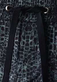 Tasche nera elastica in vita con cordino, caratterizzata da un motivo leopardato verde su tessuto morbido. Dettagli in metallo sul cordino.