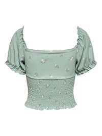 Blouse courte vert clair avec manches bouffantes, taille smockée, encolure carrée et petit imprimé floral blanc.