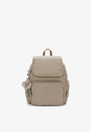 Beige nylon rugzak met een getextureerde afwerking, een klep met sluiting, een voorvak met ritssluiting, zijvakken en een zachte apensleutelhanger bevestigd.