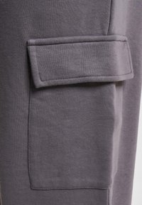 Gray sweatpants featuring a textured fabric, slim fit, and a patch pocket on the side for added functionality.