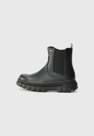 Zwarte leren Chelsea-boot met grove profielzool, elastisch zijpaneel, aantreklus en klein Tommy Hilfiger vlaglogo aan de zijkant.