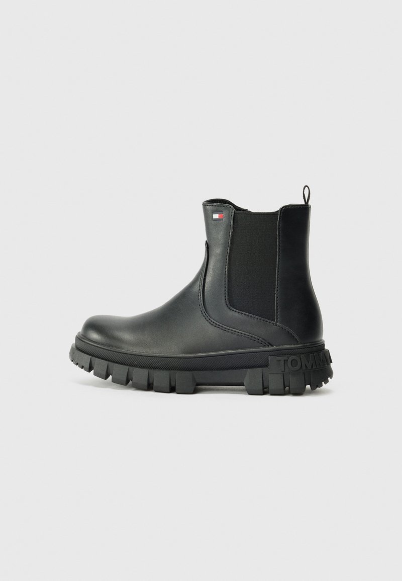 Bottine Chelsea en cuir noir avec semelle crantée épaisse, panneau latéral élastique, languette d'enfilage et petit logo drapeau Tommy Hilfiger sur le côté.