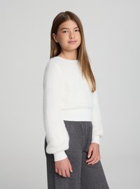 Biały, puszysty sweter z okrągłym dekoltem i balonowymi rękawami; w zestawie z szarymi spodniami z elastycznym pasem. Gładka faktura, ściągacze na mankietach.