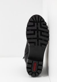 Stivale nero con suola in gomma testurizzata, caratterizzato da motivi di scolpitura profondi e un logo del marchio in rosso. Dettagli con zip laterale per una facile accessibilità.