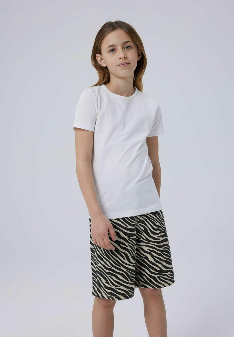 Vit kortärmad t-shirt kombinerad med beige och svarta shorts i zebramönster. Slät bomullstextur, avslappnad passform och standard rund halsringning.