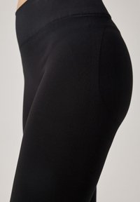 Leggings da yoga neri caratterizzati da una texture liscia e dettagli a coste lungo la vita e i lati, che evidenziano una vestibilità sagomata.