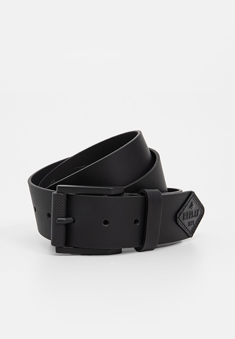Ceinture en cuir noir avec une boucle texturée, présentant une forme rectangulaire et un logo en forme de diamant estampé sur la sangle.