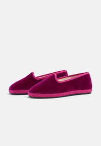 Zapatos de terciopelo sin cordones en un vibrante tono fucsia con un borde texturizado en rosa y suela negra, presentando un diseño aerodinámico y redondeado.