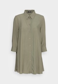 Green shirt dress with a collar, button front, and three-quarter sleeves. Features a polka dot pattern and a lightweight, smooth fabric.