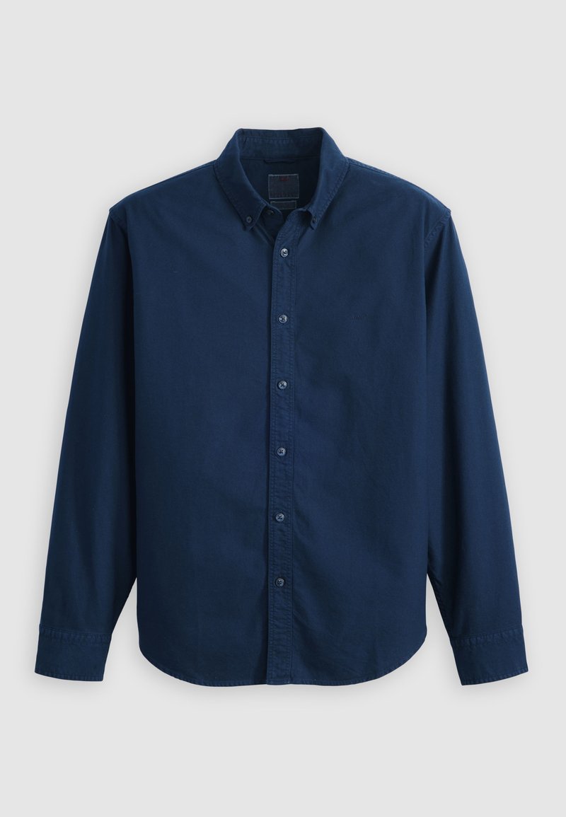Camisa de hombre azul marino de manga larga con botones y cuello sobre un fondo claro y liso.