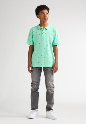 Polo vert menthe à manches courtes, col et petits motifs; assorti à un jean gris clair et des baskets blanches.