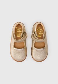Goldene Mary Jane-Schuhe mit strukturiertem Finish, runder silberner Akzent, elastischem Riemen und brauner Ledersohle. Markenlogo innen aufgedruckt.