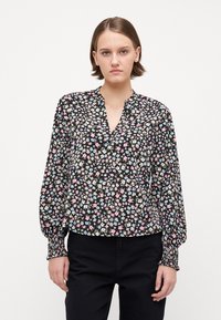 Svart blomstret bluse med nøkkelhull-neck. Har små rosa, blå og kremfargede blomster. Lange ermer med elastiske mansjetter, myk tekstur.