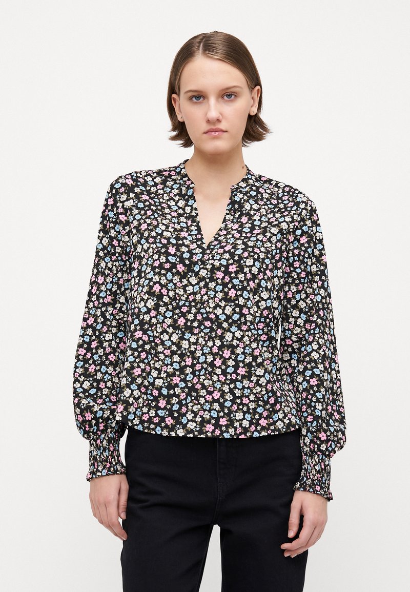 Svart blomstret bluse med nøkkelhull-neck. Har små rosa, blå og kremfargede blomster. Lange ermer med elastiske mansjetter, myk tekstur.