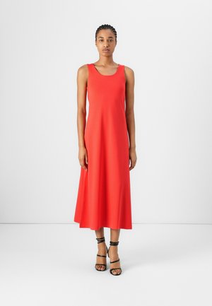 Red sleeveless dress made of smooth fabric, featuring a flared midi-length skirt. Model wears black strappy sandals and has braided hair.