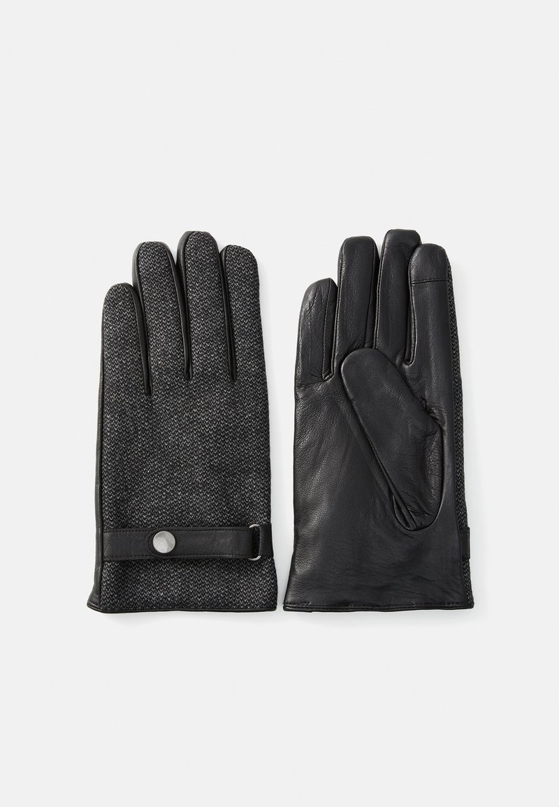 Une paire de gants noirs avec un tissu texturé sur le dessus et une paume en cuir lisse, présentant une sangle en cuir et un bouton-pression au poignet.