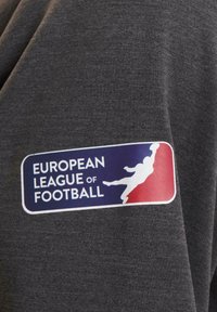 Tessuto grigio con una trama liscia, caratterizzato da un patch con logo colorato. Il patch include il testo "EUROPEAN LEAGUE OF FOOTBALL" e un grafico di un giocatore.