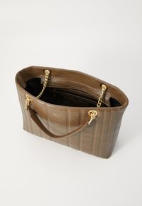 Bruine leren tote bag met een gequiltte textuur, gouden kettinghandvatten en een open bovenkant die een donkere binnenkant en een binnenzak toont.
