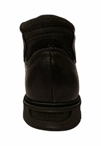 Zapato de cuero negro con parte superior texturizada, suela de goma y puntera redonda. Presenta un cuello acolchado y un branding mínimo en la suela.