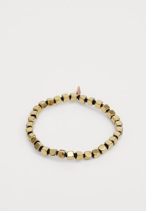 Bracciale di perline oro e nero con link a forma quadrata, alternati nei colori e con una texture liscia, fissato con un piccolo tag decorativo.